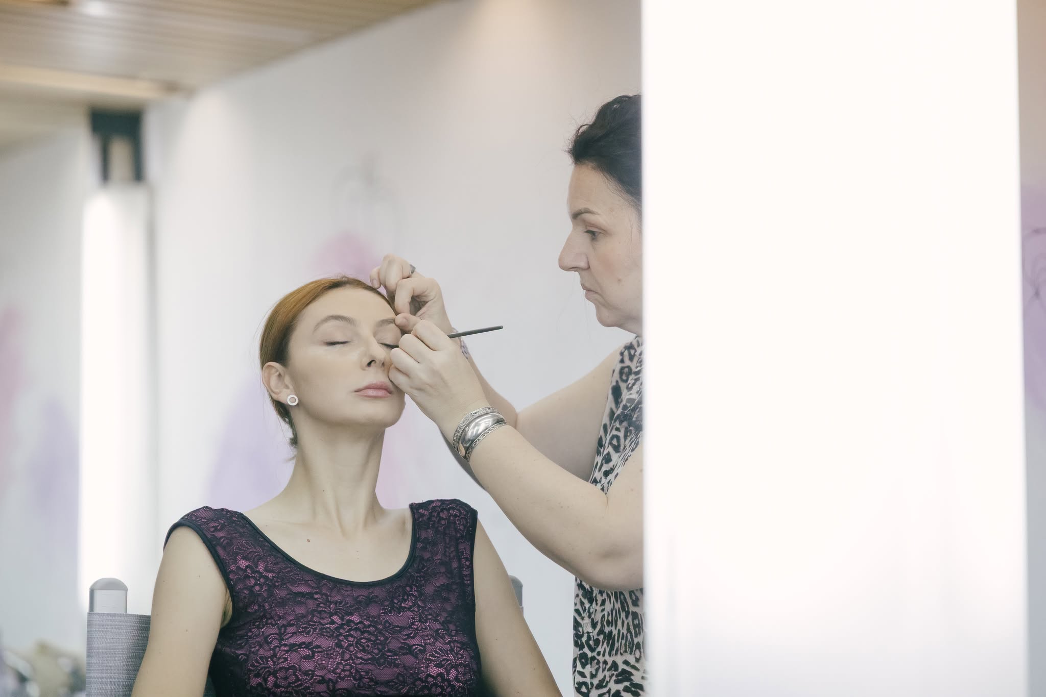 A makeup artist carefully applying eye makeup to a performer backstage before a show